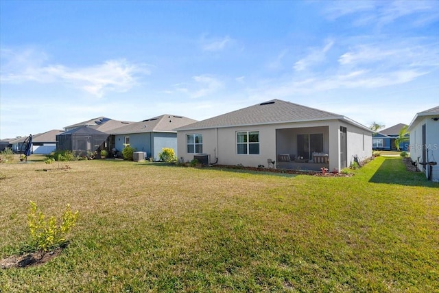 back of property with central AC and a lawn