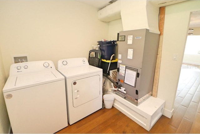 laundry room featuring wood-type flooring, heating unit, and independent washer and dryer