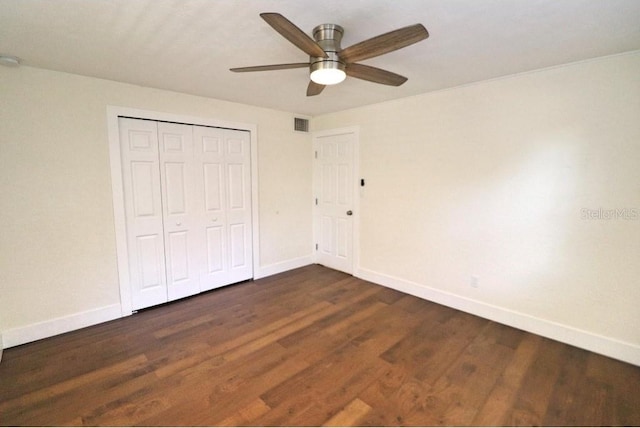 unfurnished bedroom featuring dark wood-type flooring, a closet, and ceiling fan