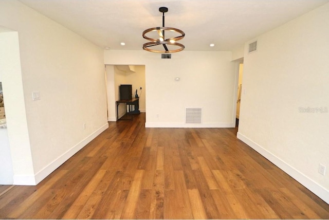 unfurnished room featuring an inviting chandelier and dark hardwood / wood-style floors