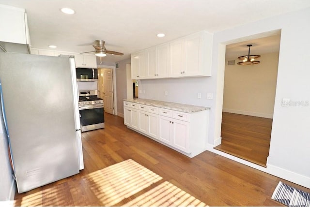 kitchen featuring white cabinets, hanging light fixtures, hardwood / wood-style flooring, ceiling fan, and stainless steel appliances