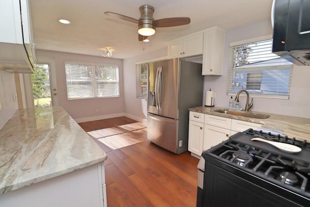 kitchen featuring sink, stainless steel fridge, black gas stove, light stone countertops, and white cabinets