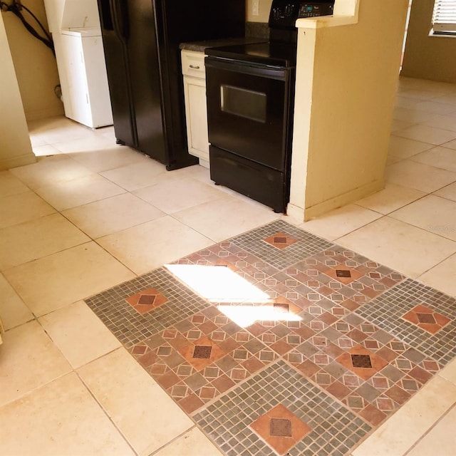 kitchen with light tile patterned floors, washer / dryer, and black appliances