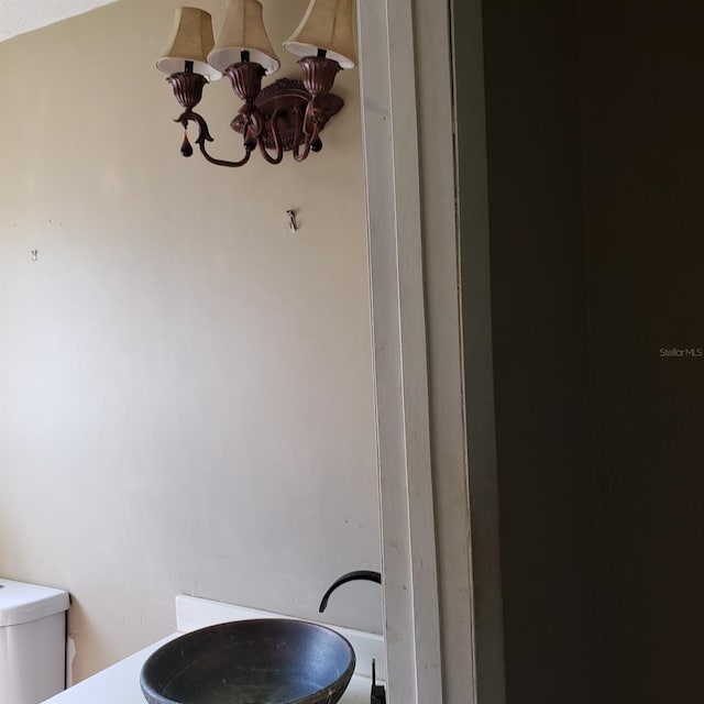 bathroom featuring sink, a chandelier, and toilet