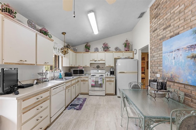 kitchen with pendant lighting, lofted ceiling, sink, white appliances, and cream cabinetry