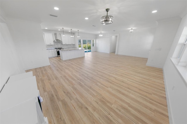 unfurnished living room featuring ornamental molding, light wood-type flooring, and visible vents