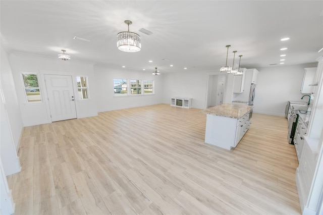 kitchen featuring decorative light fixtures, light wood-style flooring, open floor plan, white cabinets, and light stone countertops