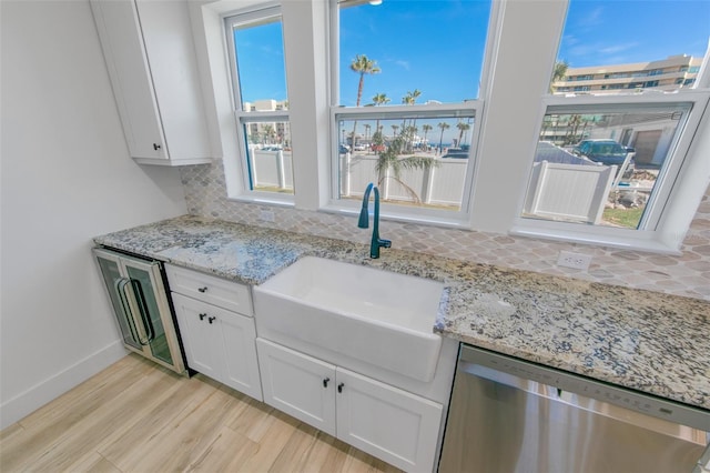 kitchen featuring white cabinets, dishwashing machine, backsplash, stainless steel dishwasher, and a sink