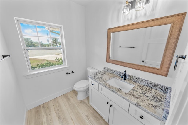 half bathroom featuring vanity, wood finished floors, toilet, and baseboards