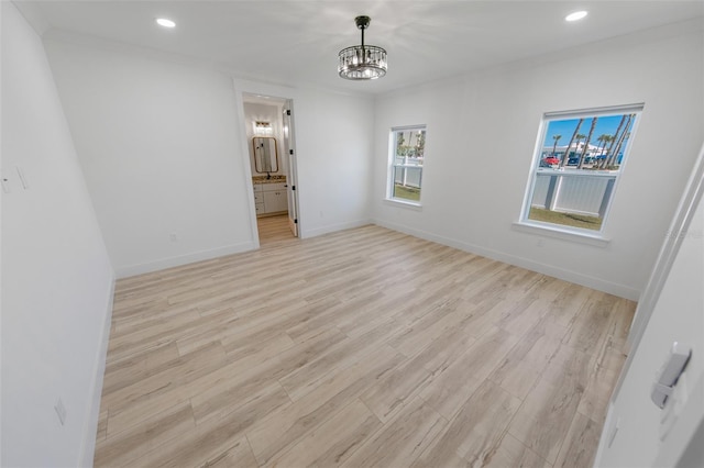 unfurnished room with baseboards, recessed lighting, an inviting chandelier, and light wood-style floors