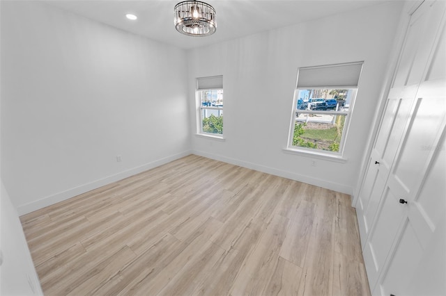 unfurnished bedroom with light wood finished floors, recessed lighting, a closet, a chandelier, and baseboards