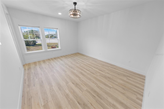 empty room featuring a chandelier, recessed lighting, light wood-style flooring, and baseboards