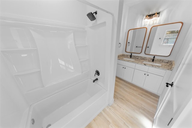 full bathroom featuring double vanity, bathtub / shower combination, a sink, and wood finished floors