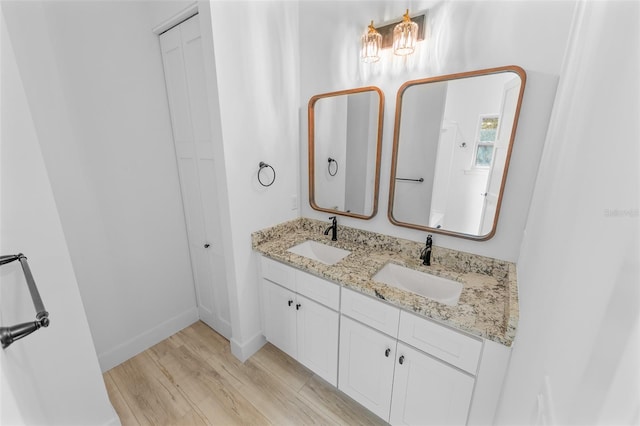 full bathroom with double vanity, a closet, a sink, and wood finished floors