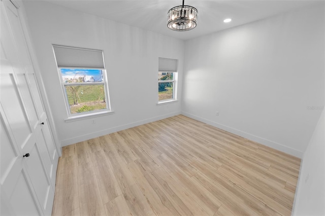 unfurnished room featuring light wood-style floors, recessed lighting, baseboards, and an inviting chandelier