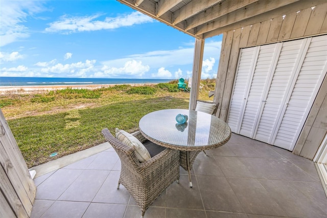 balcony featuring a patio area, a beach view, and a water view