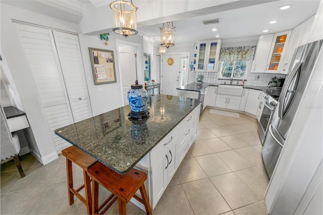 kitchen featuring a kitchen bar, light tile patterned floors, a kitchen island, dark stone counters, and white cabinets