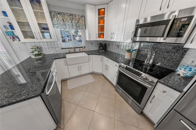 kitchen featuring sink, appliances with stainless steel finishes, dark stone counters, decorative backsplash, and white cabinets