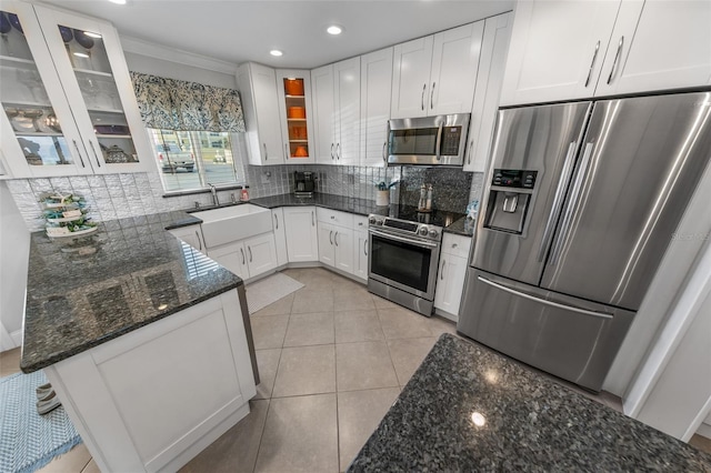 kitchen featuring sink, stainless steel appliances, tasteful backsplash, white cabinets, and dark stone counters