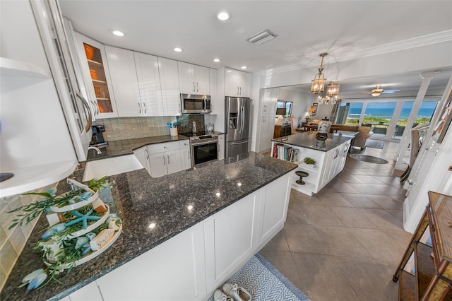 kitchen with stainless steel appliances, a kitchen island, pendant lighting, and white cabinets