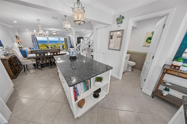 kitchen with white cabinetry, dark stone countertops, a kitchen island, and light tile patterned floors