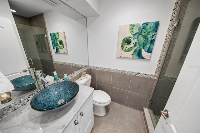 bathroom featuring walk in shower, tile patterned floors, toilet, tile walls, and vanity