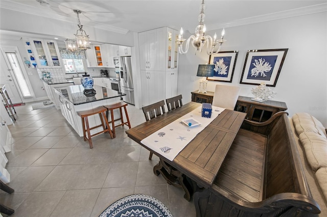 dining room featuring light tile patterned flooring, ornamental molding, and an inviting chandelier