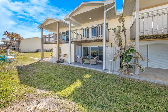 rear view of house with a patio, a balcony, and a lawn