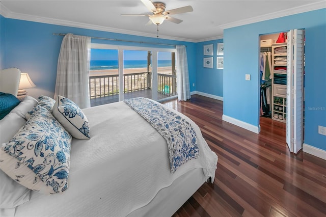 bedroom with a view of the beach, a water view, crown molding, a spacious closet, and access to exterior