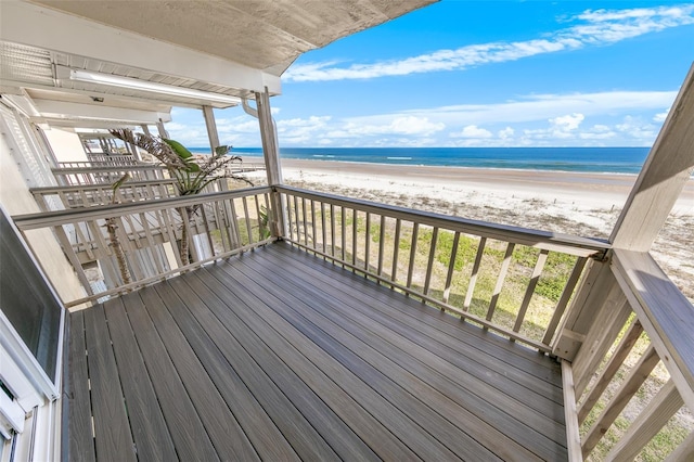 wooden deck featuring a water view and a view of the beach