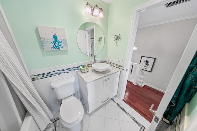 full bathroom featuring tile walls, ornamental molding, toilet, shower / bathtub combination with curtain, and tile patterned floors