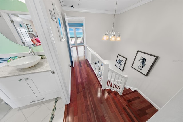 hallway with crown molding, sink, a notable chandelier, and dark hardwood / wood-style flooring