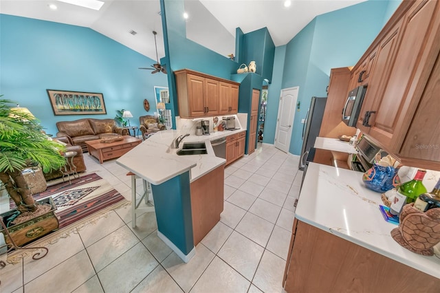 kitchen featuring sink, a breakfast bar area, light stone counters, kitchen peninsula, and stainless steel appliances