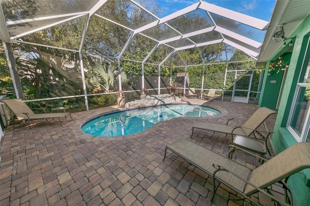 view of pool with a patio area and glass enclosure