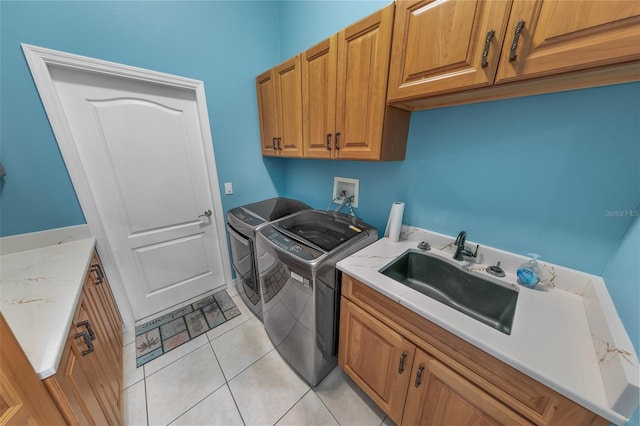 laundry room featuring light tile patterned flooring, cabinets, sink, and washing machine and dryer