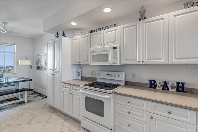 kitchen with light tile patterned floors, white cabinets, and white appliances