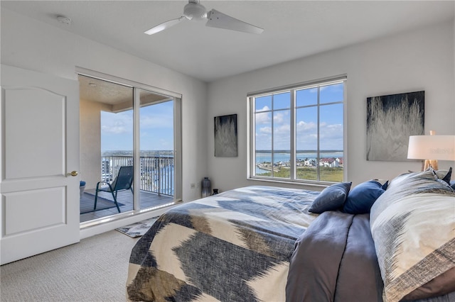 carpeted bedroom with multiple windows, a water view, access to exterior, and ceiling fan