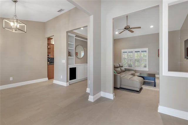 living room featuring ceiling fan with notable chandelier and built in features