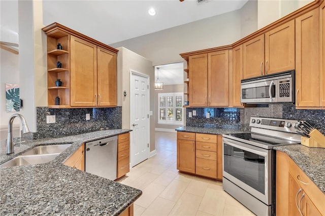 kitchen with appliances with stainless steel finishes, sink, decorative backsplash, and dark stone counters