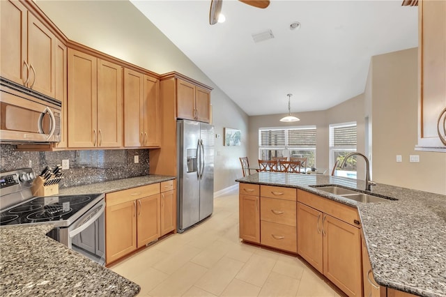 kitchen with appliances with stainless steel finishes, sink, hanging light fixtures, and dark stone countertops