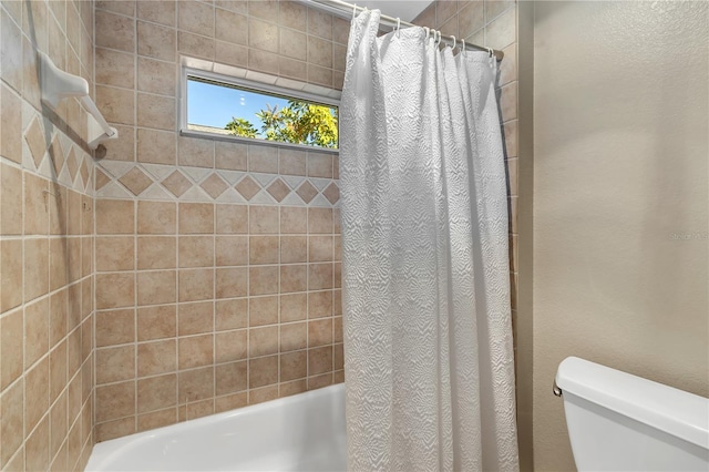 bathroom featuring toilet and shower / bath combo with shower curtain