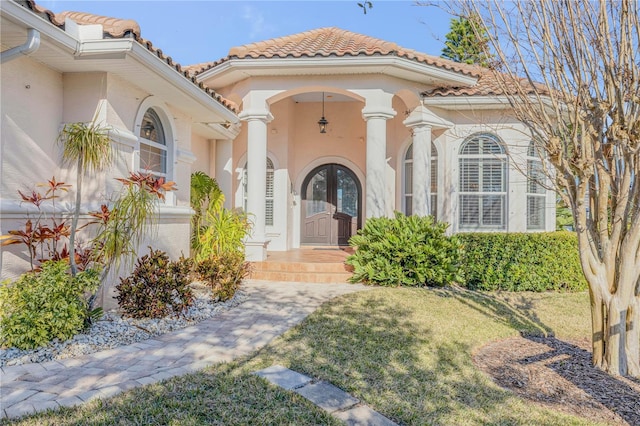 entrance to property with french doors and a lawn