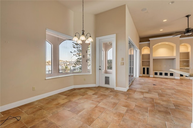 unfurnished dining area featuring built in shelves and ceiling fan with notable chandelier