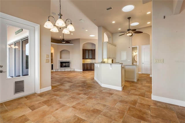 kitchen featuring hanging light fixtures, a center island, ceiling fan with notable chandelier, and cream cabinetry