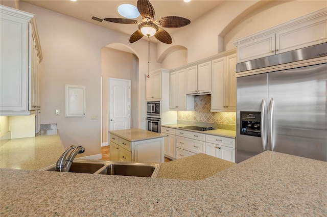 kitchen featuring sink, built in appliances, a center island, ceiling fan, and decorative backsplash