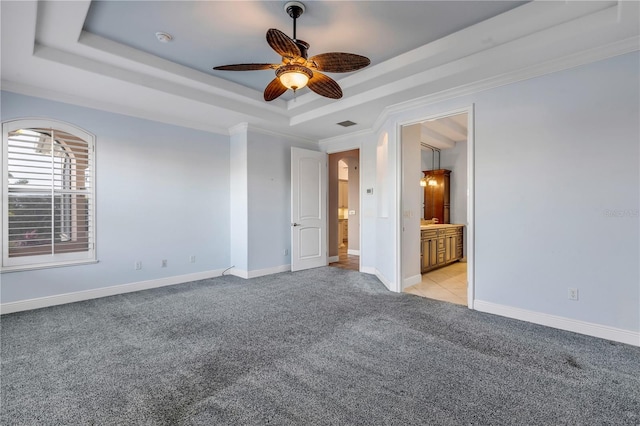 empty room featuring ceiling fan, light colored carpet, ornamental molding, and a raised ceiling