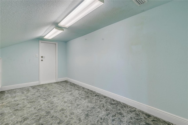 additional living space with vaulted ceiling, a textured ceiling, and carpet