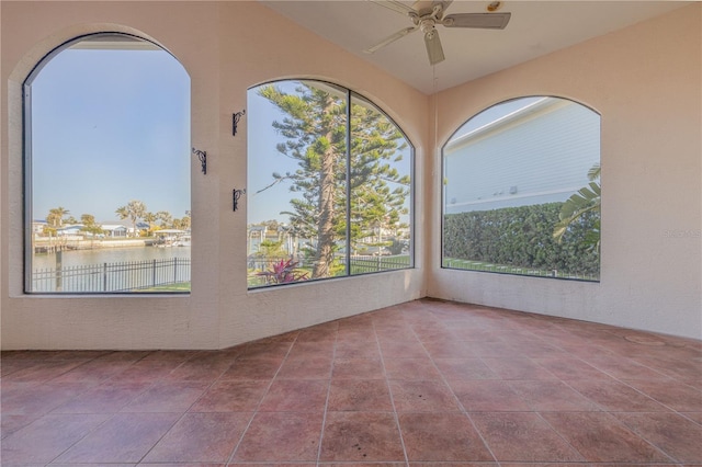 unfurnished sunroom featuring ceiling fan and a water view