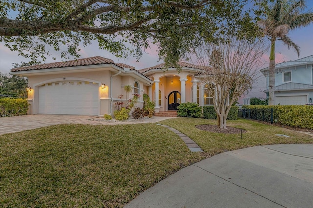 mediterranean / spanish house with a garage and a yard