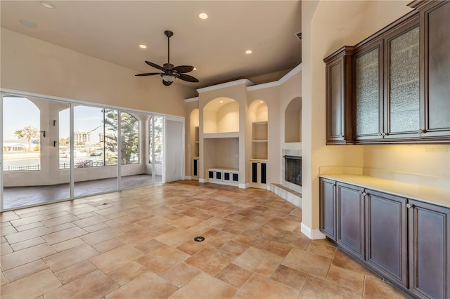 unfurnished living room featuring built in shelves and ceiling fan